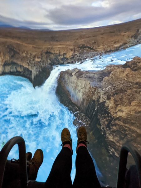 Legs on a ride over a video screen showing a waterfall at Flyover Iceland Reykjavik