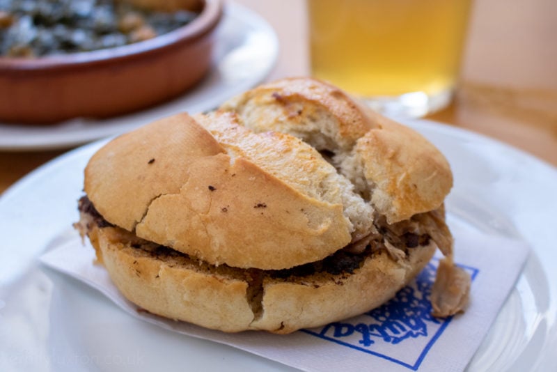 close up of a crusty roll filld with meat called a Montadito de Pringa