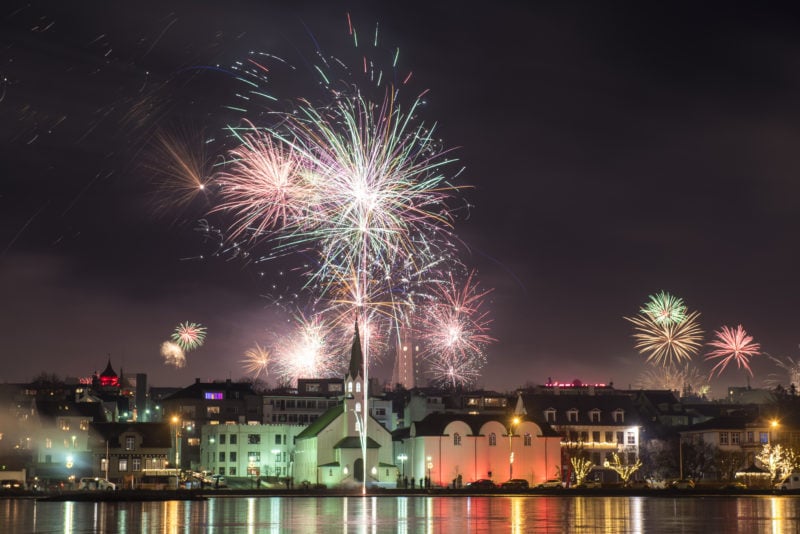 new years eve fireworks above buildings on the edge of a harbour in Reykjavik at night