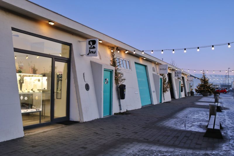 a row of shows in white buildings with a slanted front wall and turquoise doors