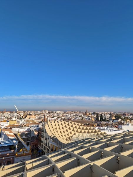 Looking out across a white geometric architecture with Seville in the background under a clear blue winter sky