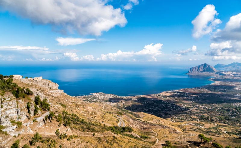 looking down at a mountain walking trail in sicily towards the blue sea