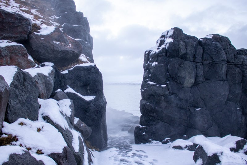 snow covered path leading between black rocks