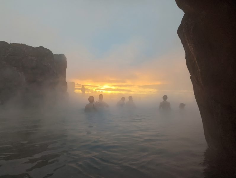 Sunset viewed through steam between silhouetted cliffs at Sky Lagoon in Reykjavik Iceland