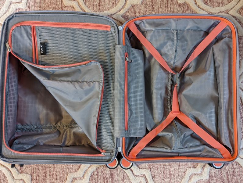 looking down at an open suitcase with grey interior and orange straps