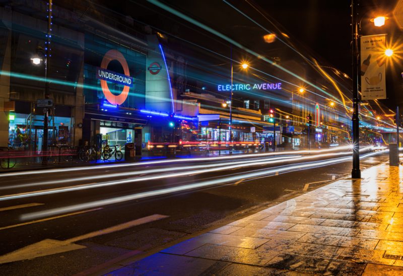 night shot with blurred streaks of light from traffic passing in front of brixton tube station