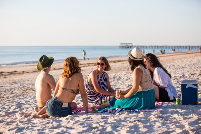 groupd of men and women in a circle on the beach with the sea in the background on a working holiday visa in adelaide south australia
