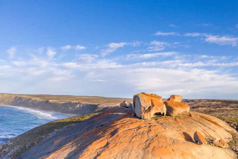 orange rocks on top of a cliff with a beach in the background on kangaroo island in south australia 