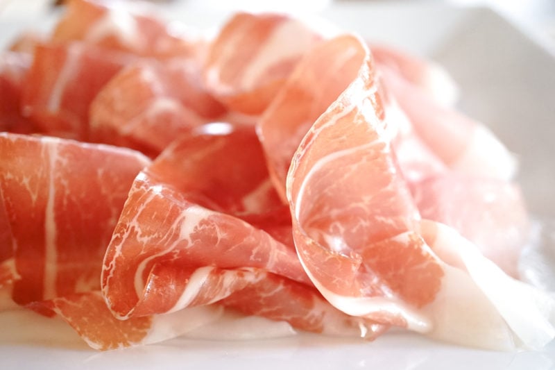 close up of several thin slices of pale pink parma ham 