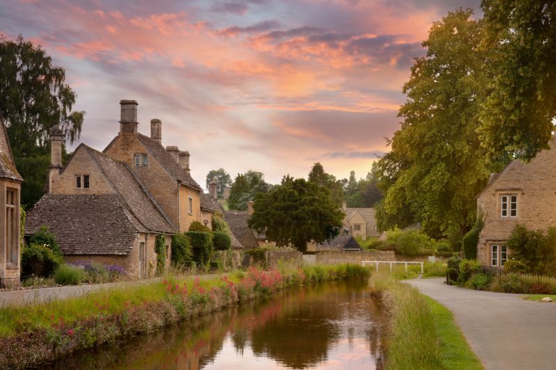 sunset over a small village with beige buildings and a wide flat river