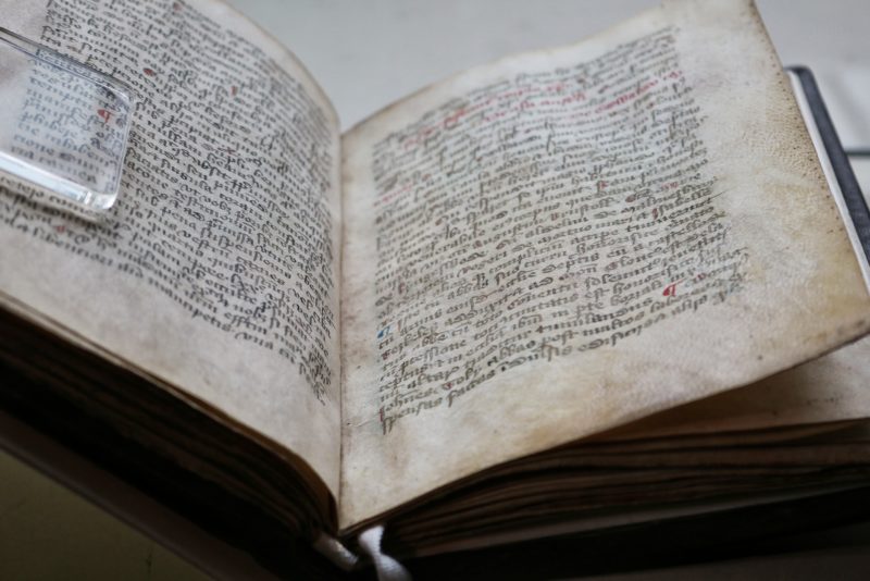 close up of a very old open book with thick pages made from skin and saxon writing in black ink