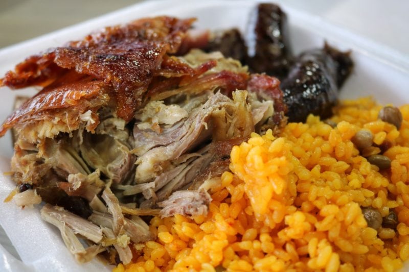 close up of a white takeaway box containing lechon roast pork with crackling and yellow rice