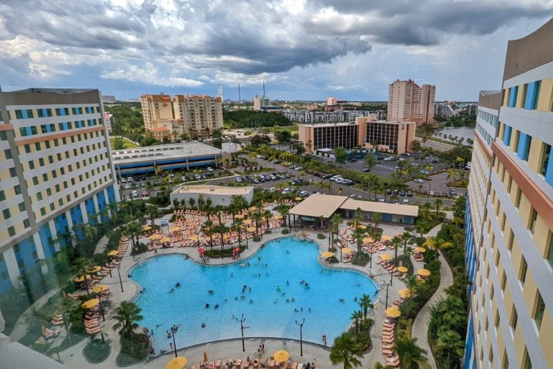 looking down from a hotel room window at a curved blue pool on a cloudy day with various other hotels and buildings in the background - budget accommodation at universal studios in orlando florida