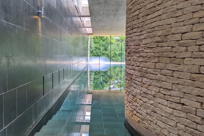 empty pool in a spa with a window at the far end looking out onto green trees