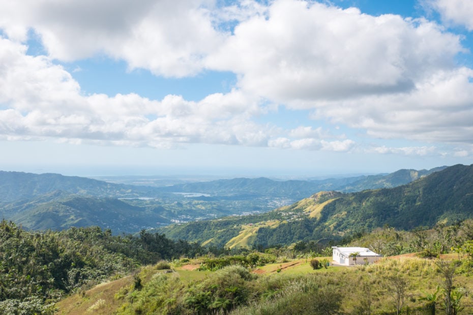 view of a green mountain landscape on a sunny day with a blue sky filled with fluffy white clouds