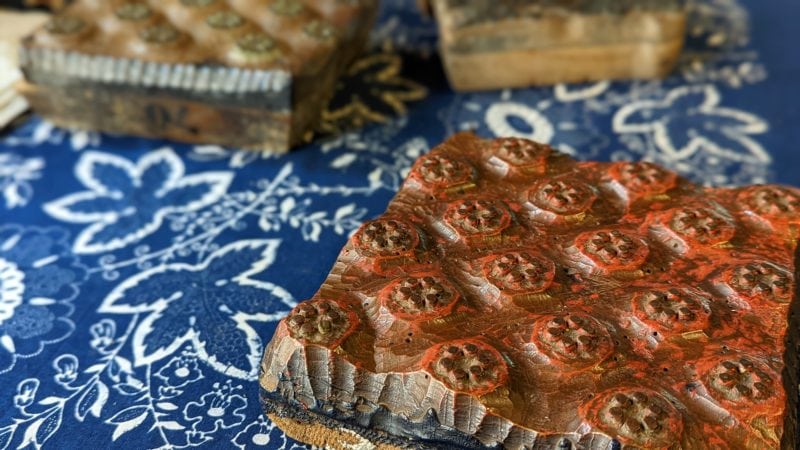 a wooden mould with a floral pattern sitting on top of a dark blue fabric with a white pattern of leaves on it inside the Danzinger blueprinting workshop in South Moravia near Brno