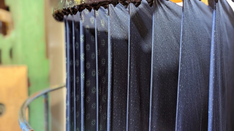 a row of blue sheets of fabric handing from a wooden rail at Danzinger Blueprint workshop - best day trips from Brno