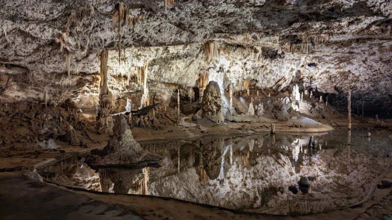 Inside a cave with many stalegtites and stalegmites reflected in the calm water of a small pond. Punkva Caves in South Moravia on a day trip from Brno. 