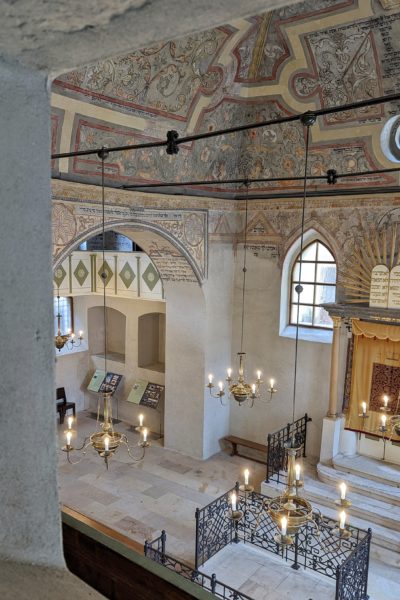 Interior of a synagogue with a painted ceiling and white stone walls