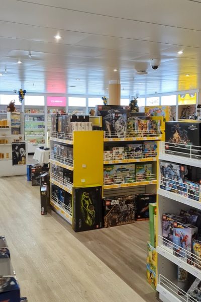 interior of a shop with two large stands displaying many boxes of lego. in the background are white shelves full of perfume. 