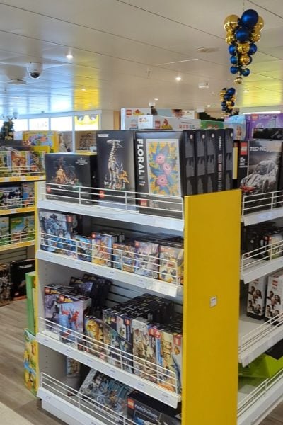 close up of a bright yellow stand with found shelves full of boxes of lego insid ehte DFDS duty free shop on the ferry to france