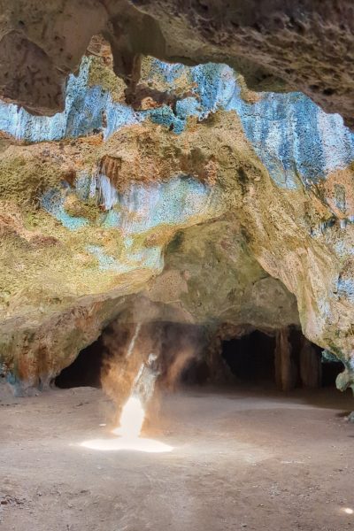Debu tebal berputar-putar dalam seberkas cahaya melalui gua berbatu di Aruba