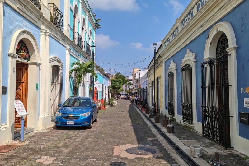 stone street in Villahermosa Centro Historico with pastel blue buildings on either side on a very sunny with blue sky above