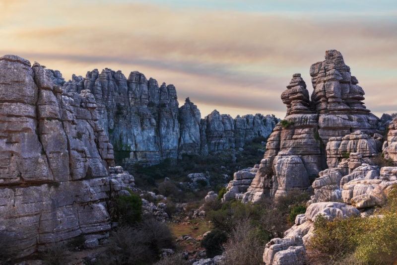 rocky valley with bizarely shaped grey rock formations pointing upwards near sunset with a pinkish sky overhead at El Torcal de Antequera in Andalucia Spain