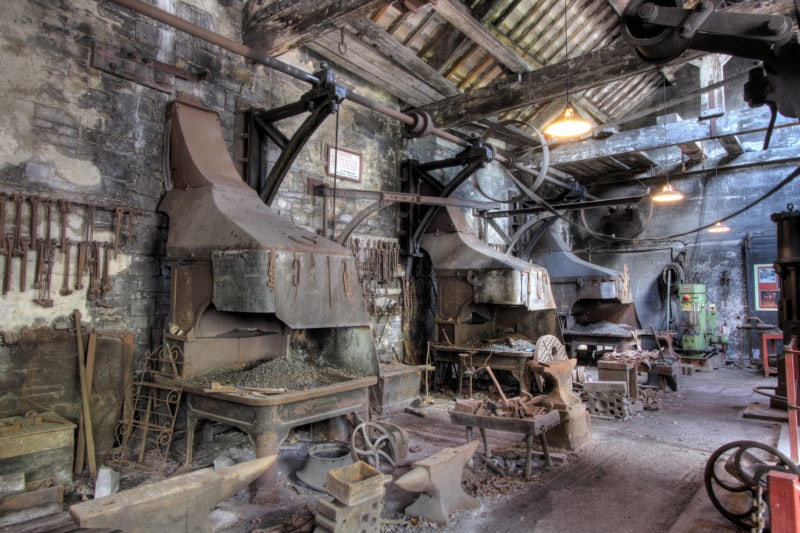 interior of a large grey conrete warehouse building filled with old metal machinary from the Victorian era - the National Slate Museum in Llanberis