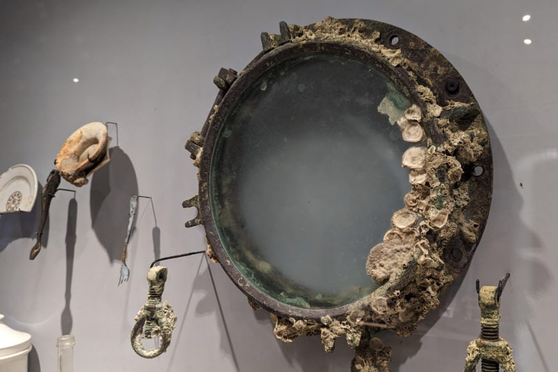 close up of an old porthole frame mounted on a wall and covered in barnacles because it has been under the sea for a long time - in the museum of subaquatic archeology in campeche