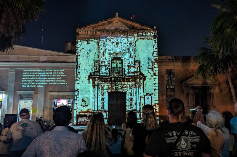 exterior of Casa Montejo in Merida at night lit up by white lights with a crowd silhouetted in front. 