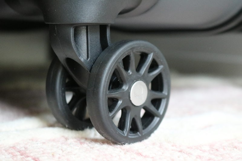 close up of a black plastic wheel on the bottom of a hard shell suitcase. antler clifton review. 