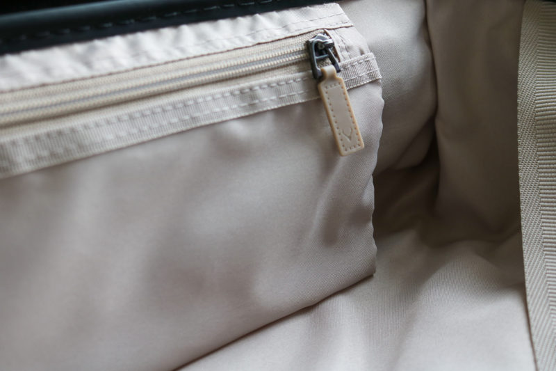 close up of a small interior pocket inside a suitcase made from grey fabric with grey zips.