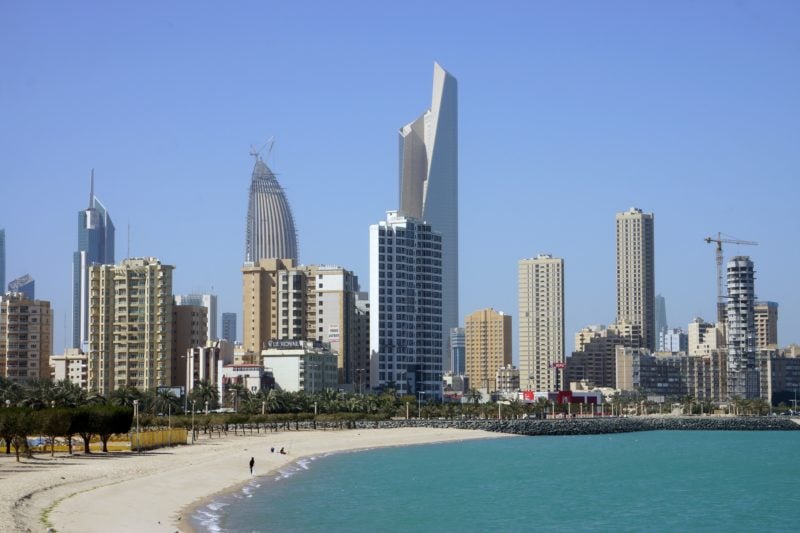 kuwait skyline with lots of skyscrapers behind a sandy beach and the sea