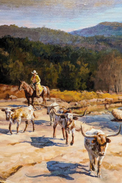 close up of a section of an oil painting showing a cowboy in a long yellow coat and white stetson hat on a brown horse herding longhorn cattle along a river valley.