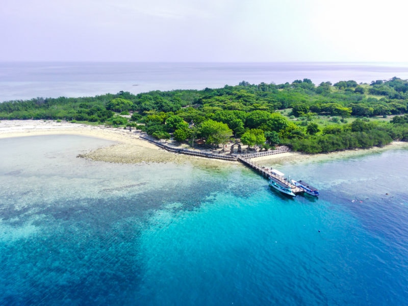  Aerial footage taken with drone of Menjangan Island, West Bali National Park, Indonesia - a small island covered in lush green forest and surrounded by vivid turquiose water. 