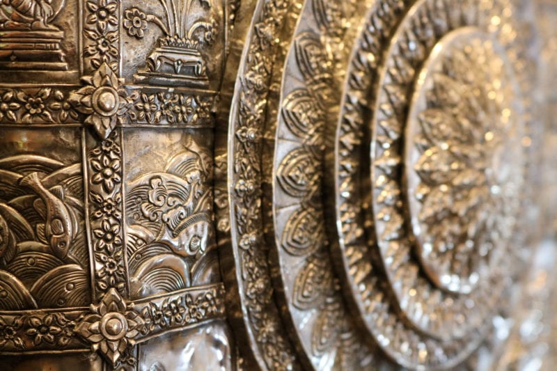 close up of part of a large silver shield with several circles carved one inside the other and intricate carvings of flowers and landscapes in between each ring