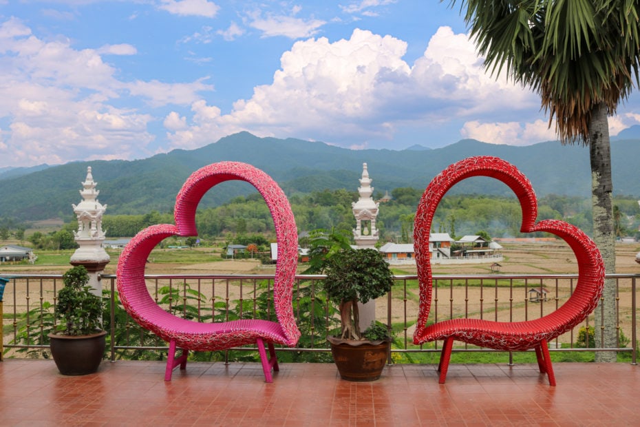 two large pink heartshaped frames in front of a view of green countryside with distant mountains in Nan Province Thailand