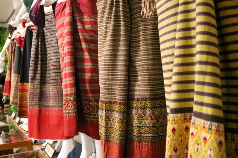 close up of the lower half of a line of mannequins wearing traditional long woven skirts from northern thailand