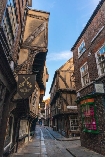 narrow conbbled street in York lined with medieval buildings all different shapes and sizes 