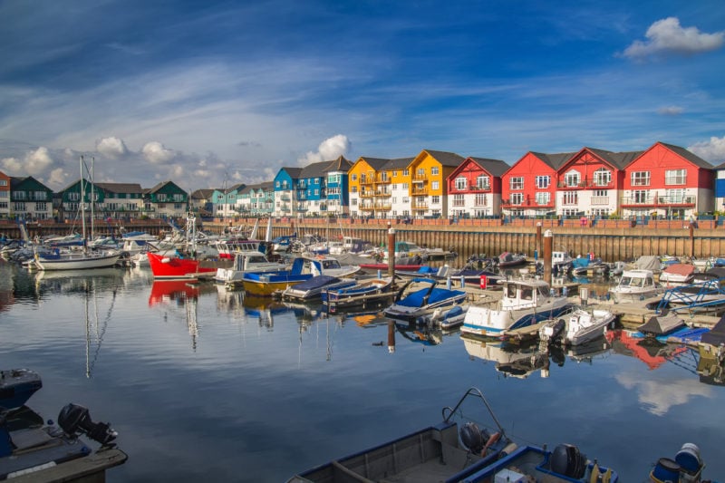 A small and cozy harbor in the town of Exmouth. There are many vessels moored here. Around the harbor are colorful beautiful houses. Devon. England