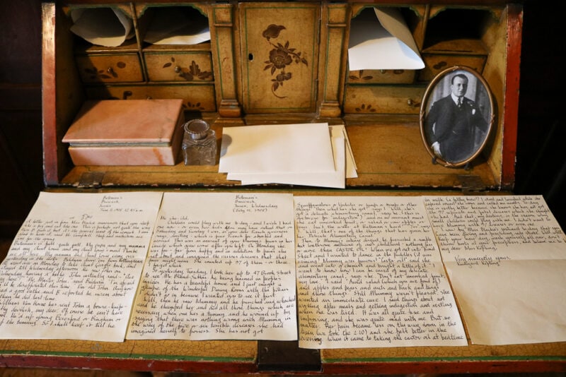 close up of Rudyard Kipling's writing desk with hand written letters laid out across the desk next to a framed photo of the author