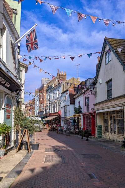 george street in hastings on a sunny day with shops on either side and colourful bunting overhead