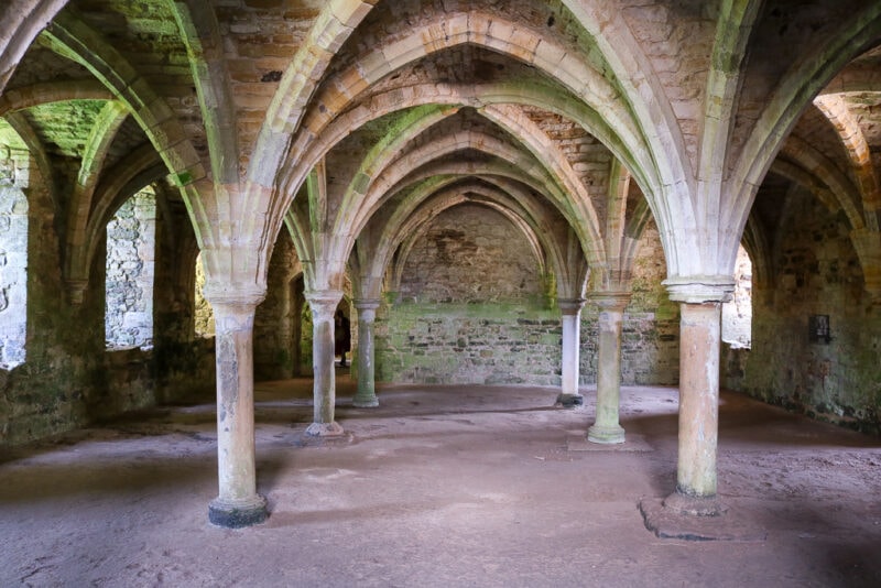 interior of norman abbey cloisters at Battle Abbey with stone pillars and arches