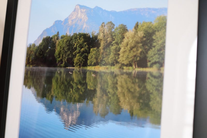 close up of a photo in a frame showing a mountain and trees reflected in a blue lake