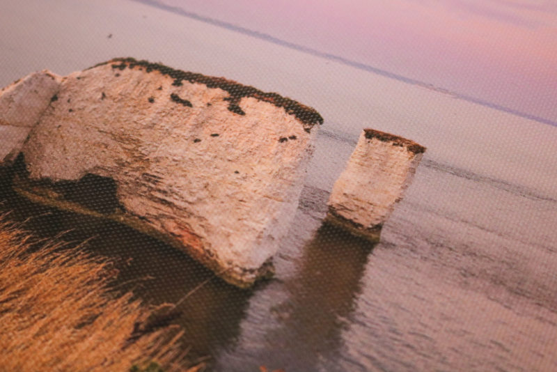 close up of a photo printed on canvas with two chalk rock stacks in the sea surrounded by pink sunset sky