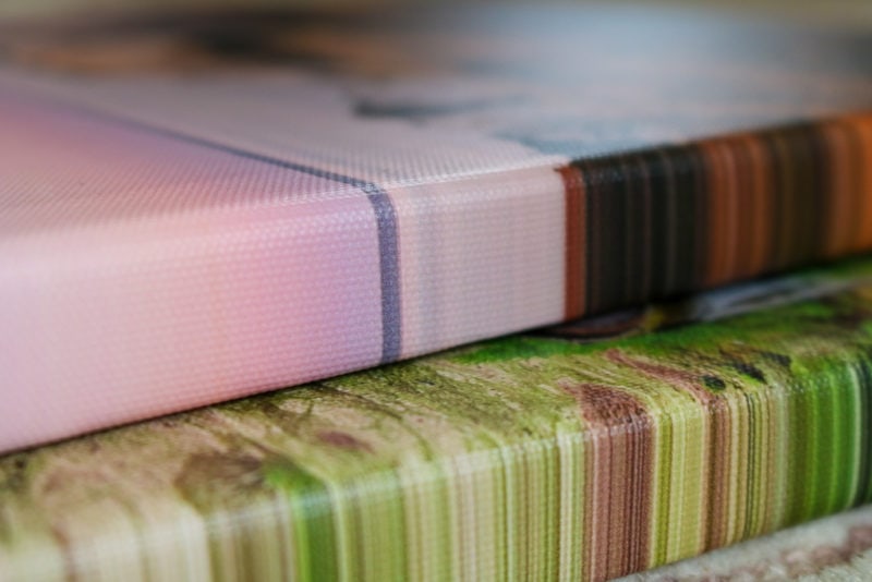 close up of the edge of two canvas prints, one is pink and one is green