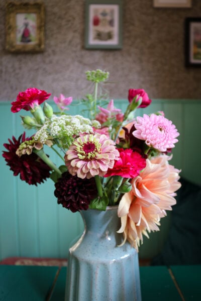 close up of a bunch of different pink and orange flowers in a light blue ceramic vase