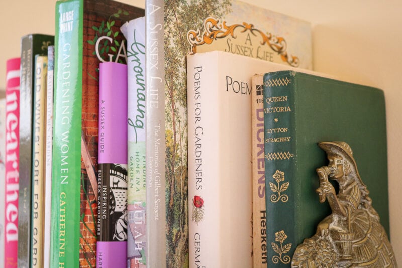 close up of books on a bookshelf with a brass bookend shaped like a woman in a large Victorian style dress
