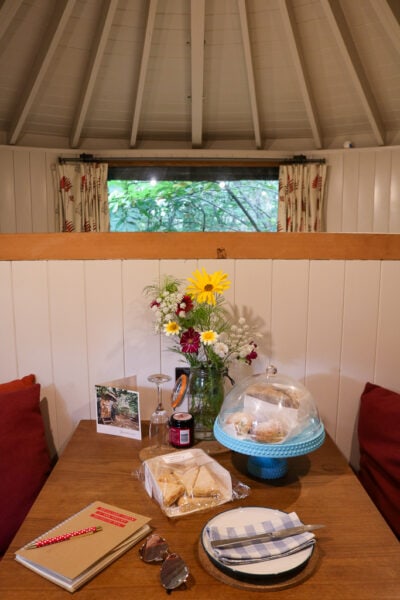 wooden table in a cabin with a cake stand and a bunch of flowers in a vase